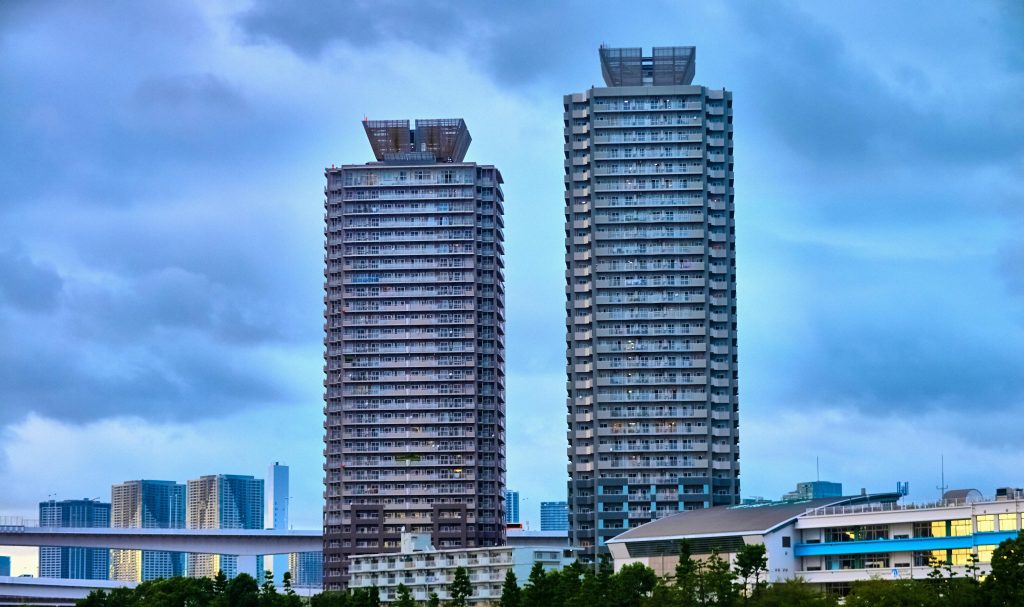 Capture of two modern high-rise buildings in Tokyo against a blue sky.